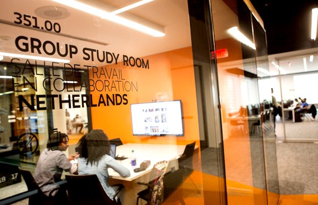 Two students at table in glass-walled room